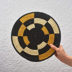 hand holding a yellow and black patterned woven placemat